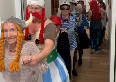 Bewohner:innen in Kostümen in einer Polonaise im Flur, darunter Wikinger- und Matrosenkostüme.