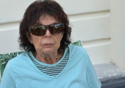Teilnehmerin des ViWo Grillfests 2025 mit Sonnenbrille sitzt im Freien, hellblaues T‑Shirt