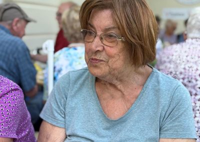 Porträt einer Teilnehmerin in grauem T‑Shirt beim ViWo Grillfest, im Hintergrund Gäste und ein Rotkreuz‑Logo.