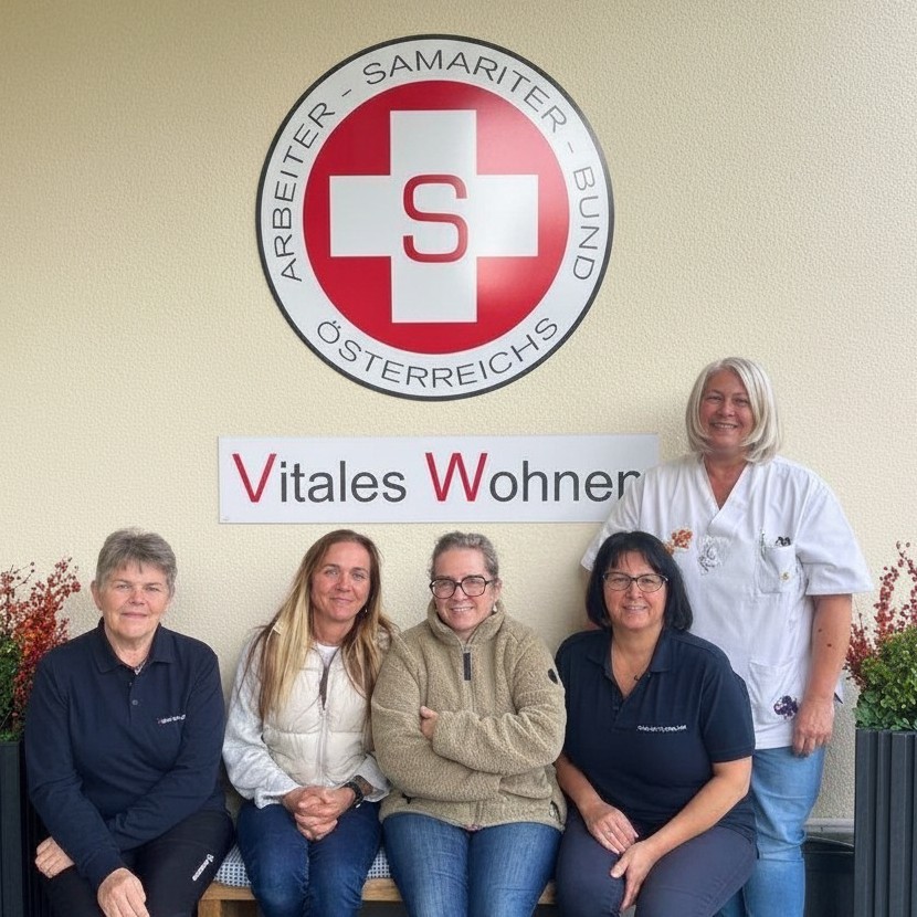 Fünf Frauen (vier sitzend, eine stehend) vor Wand mit Samariter-Logo und Schild "Vitale Wohnen".